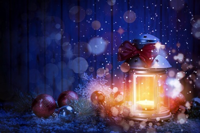 Image of Christmas lantern with burning candle and festive decor on table. Magical atmosphere