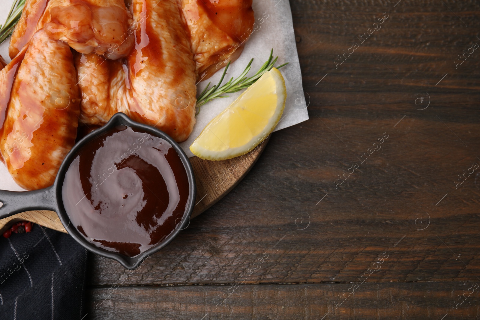 Photo of Fresh marinade, raw chicken wings and lemon on wooden table, top view. Space for text