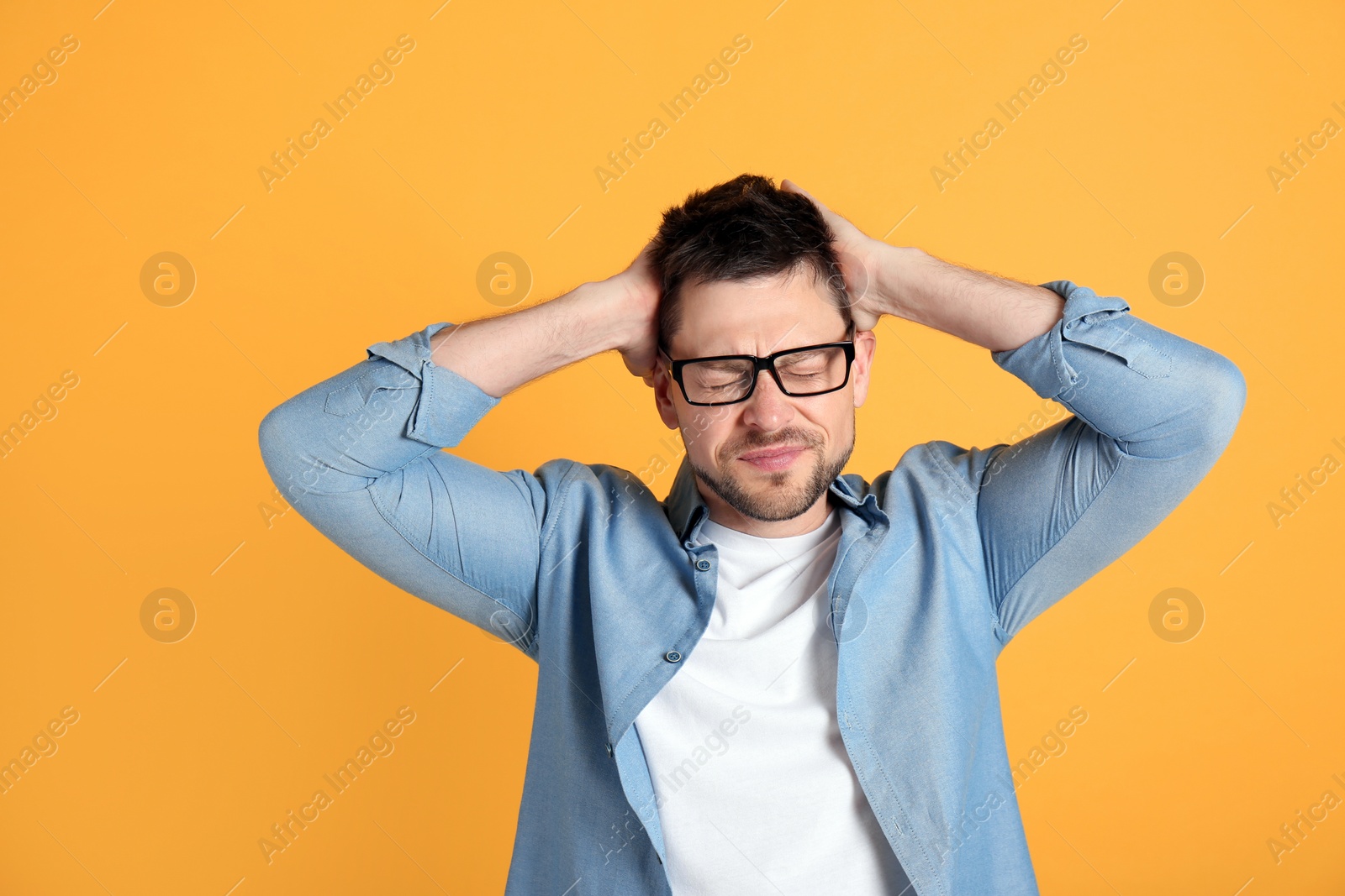 Photo of Man suffering from terrible migraine on yellow background