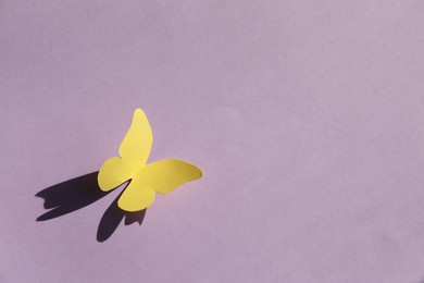 Yellow paper butterfly on violet background, top view. Space for text