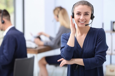 Photo of Young female receptionist with headset in office