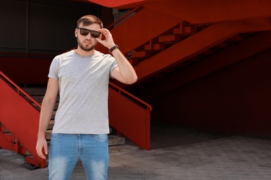 Photo of Young man wearing gray t-shirt on street. Urban style