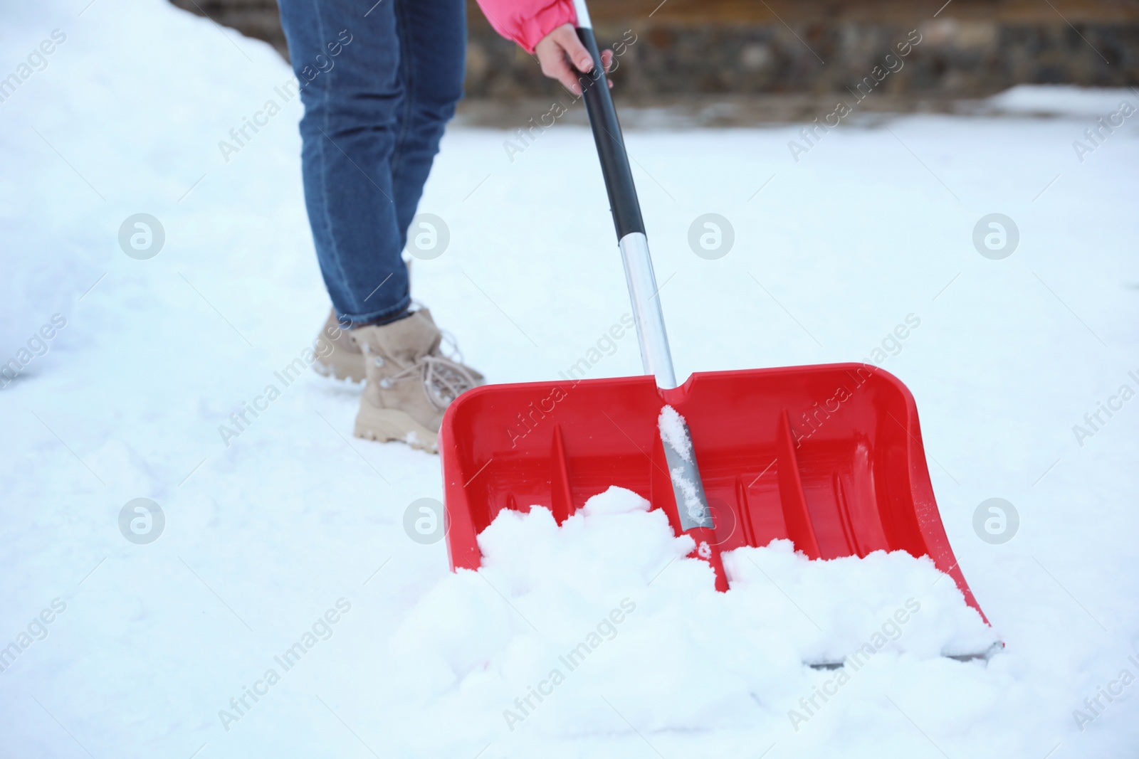 Photo of Woman cleaning snow with shovel outdoors on winter day, closeup