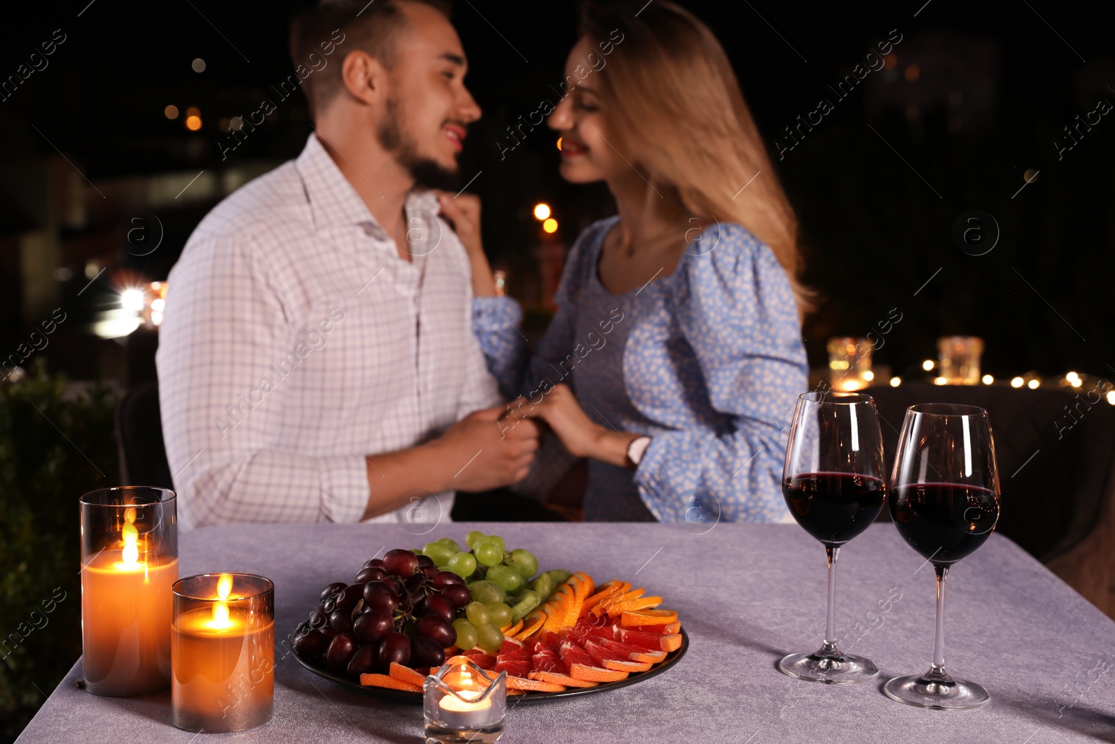 Photo of Romantic couple at cafe terrace in evening, focus on table