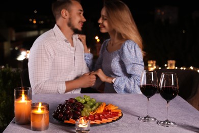 Photo of Romantic couple at cafe terrace in evening, focus on table