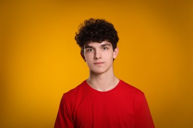 Photo of Portrait of cute teenage boy on orange background