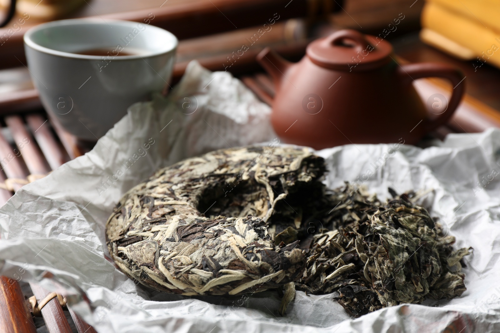 Photo of Broken disc shaped pu-erh tea on wooden tray, closeup. Traditional ceremony