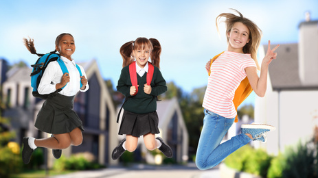 Image of Happy girls jumping on street. School holidays