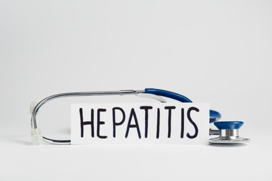 Photo of Word Hepatitis and stethoscope on white background