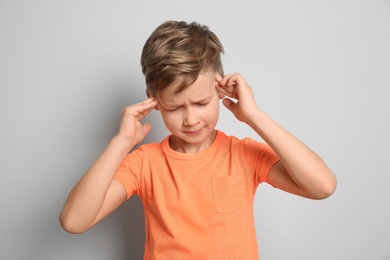 Little boy suffering from headache on grey background