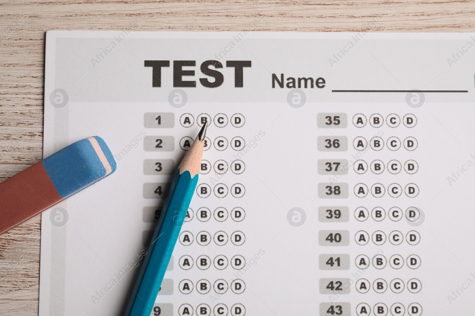 Photo of Answer sheet, pencil and eraser on wooden table, top view. Student passing exam