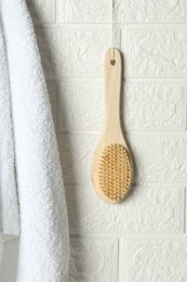 Photo of Bath accessories. Bamboo brush and terry towel on white brick wall