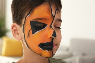 Photo of Cute little boy with face painting indoors, closeup