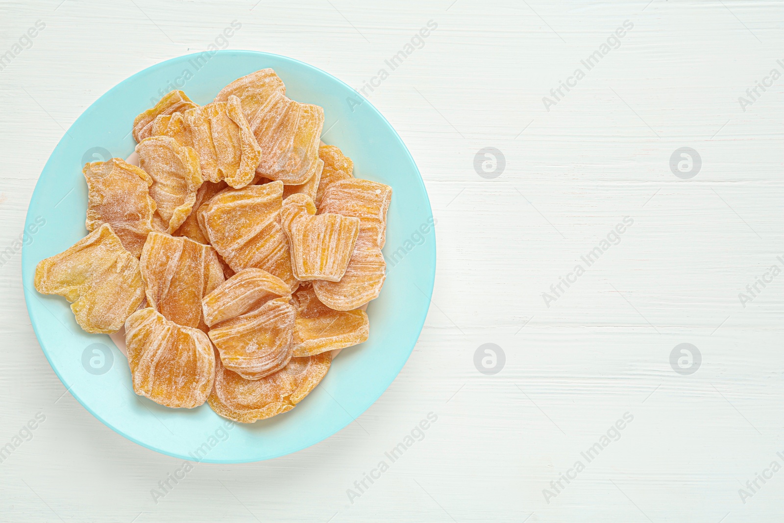 Photo of Delicious dried jackfruit slices on white wooden table, top view. Space for text