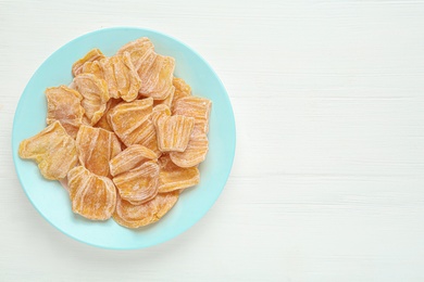 Photo of Delicious dried jackfruit slices on white wooden table, top view. Space for text