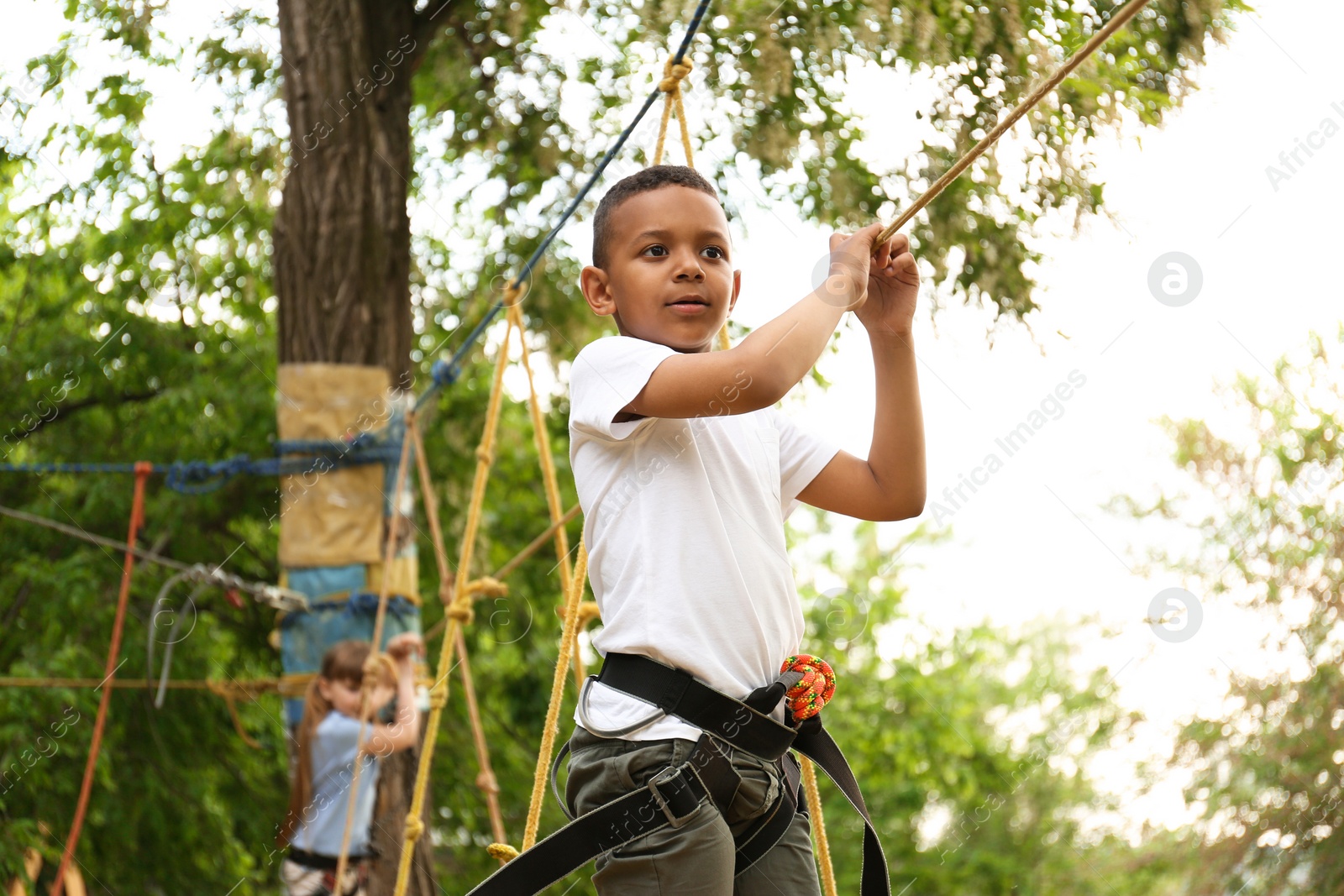 Photo of Little African-American boy climbing in adventure park. Summer camp