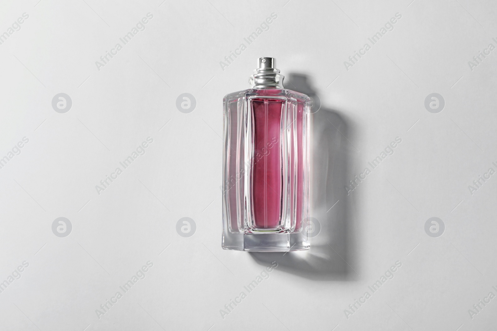 Photo of Bottle of perfume on light background, top view