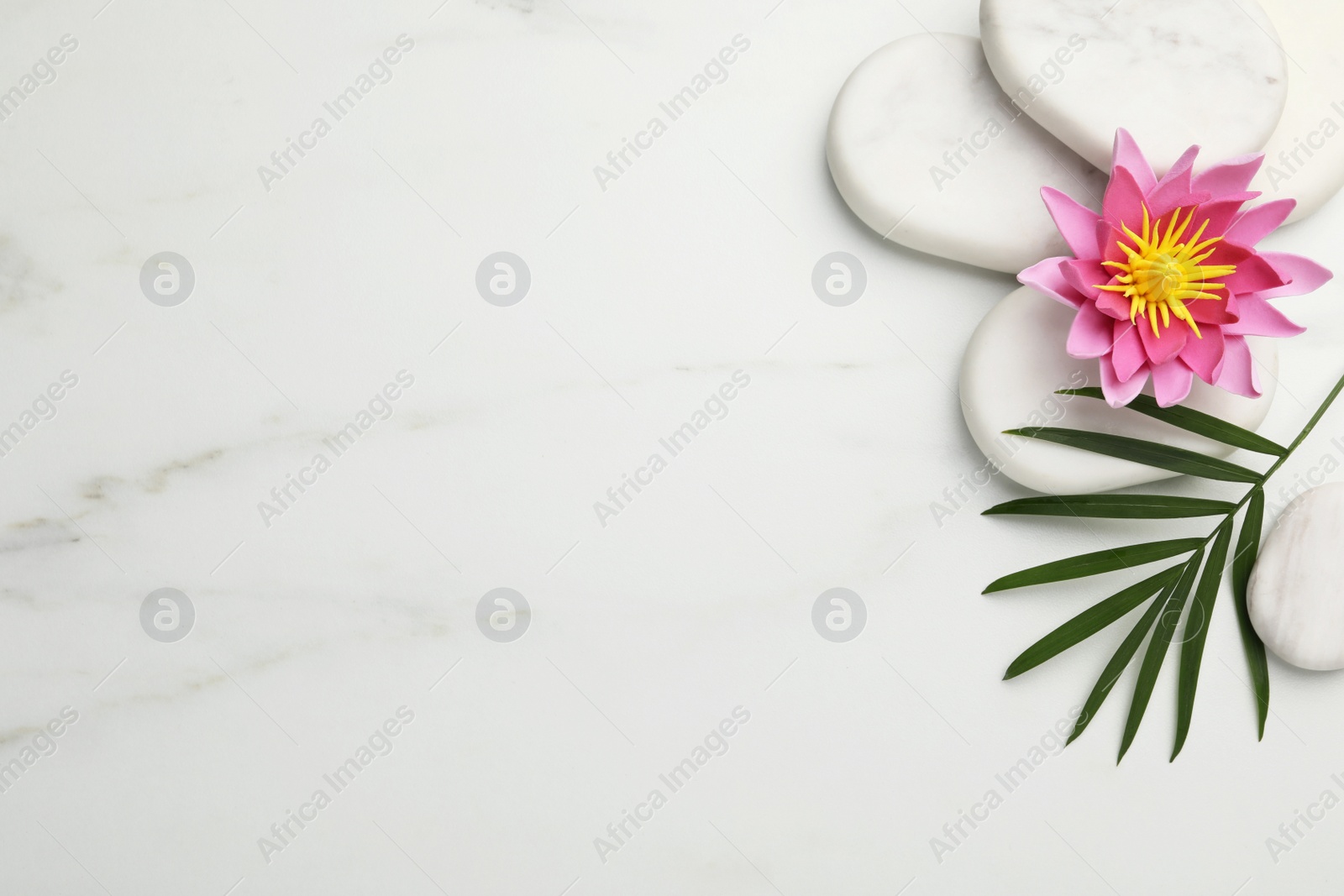 Photo of Flat lay composition with spa stones, lotus flower and leaf on white marble table. Space for text