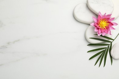 Photo of Flat lay composition with spa stones, lotus flower and leaf on white marble table. Space for text