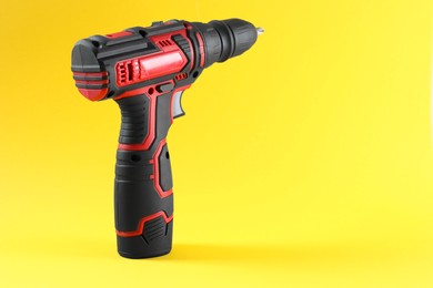 Modern electric screwdriver on yellow background. Space for text