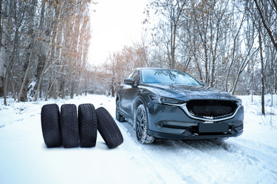 Snow tires near car on road in winter