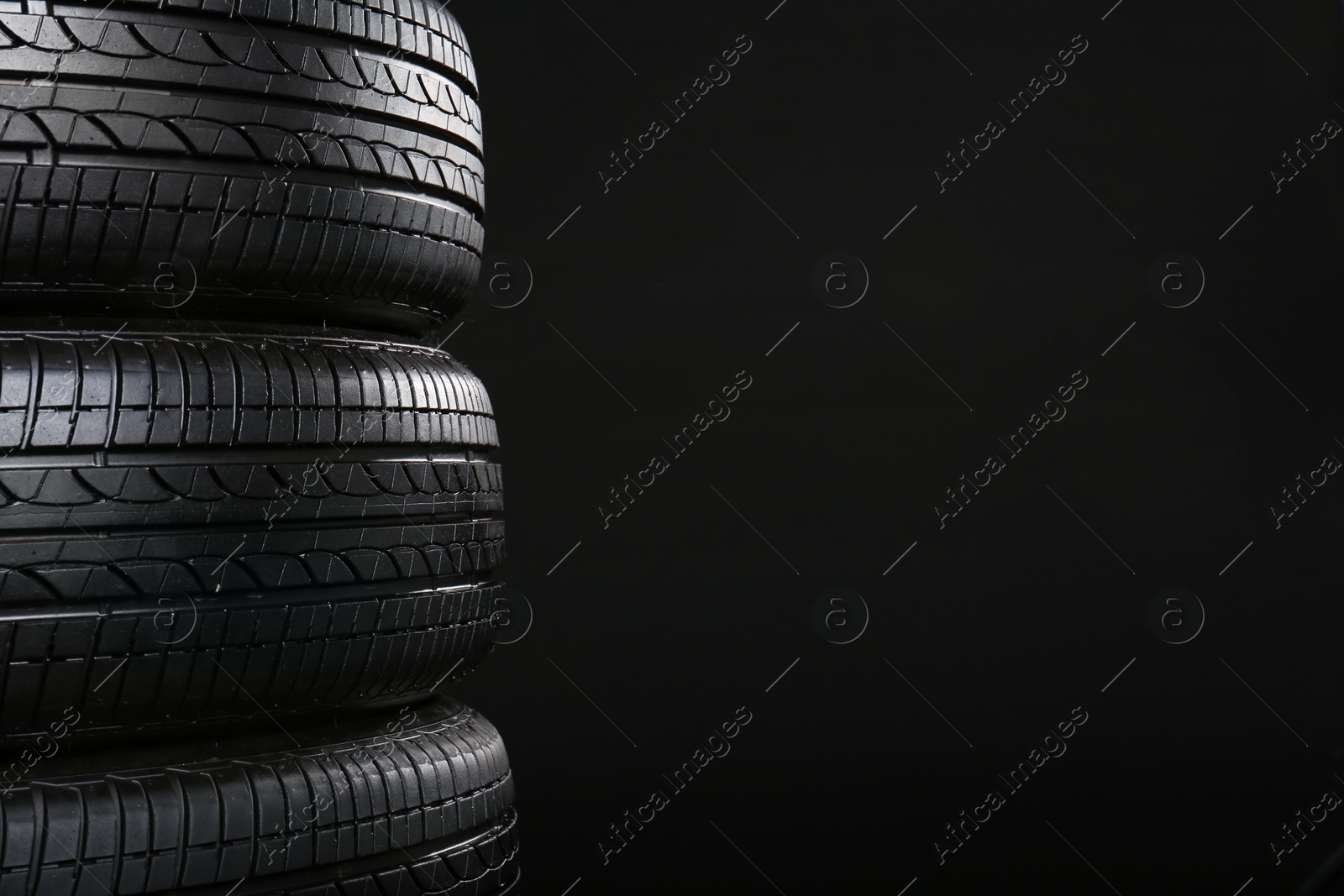 Photo of Stack of car tires on black background, closeup