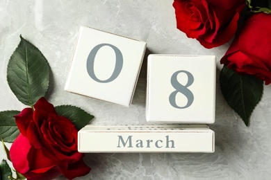 Block calendar with date 8th of March and roses on light grey marble background, flat lay. International Women's Day