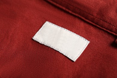 Photo of Blank clothing label on red shirt, closeup