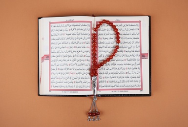 Muslim prayer beads and Quran on color background, top view