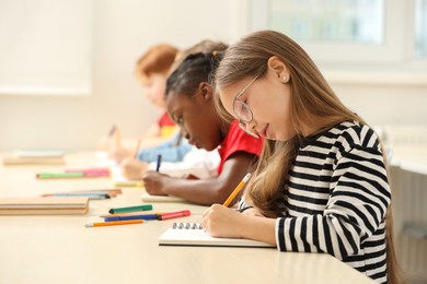 Photo of Cute children studying in classroom at school. Space for text