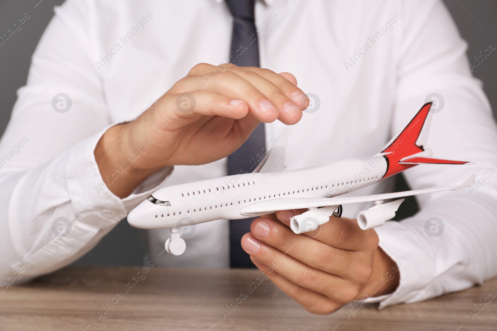 Photo of Insurance agent covering toy plane at table, closeup. Travel safety concept