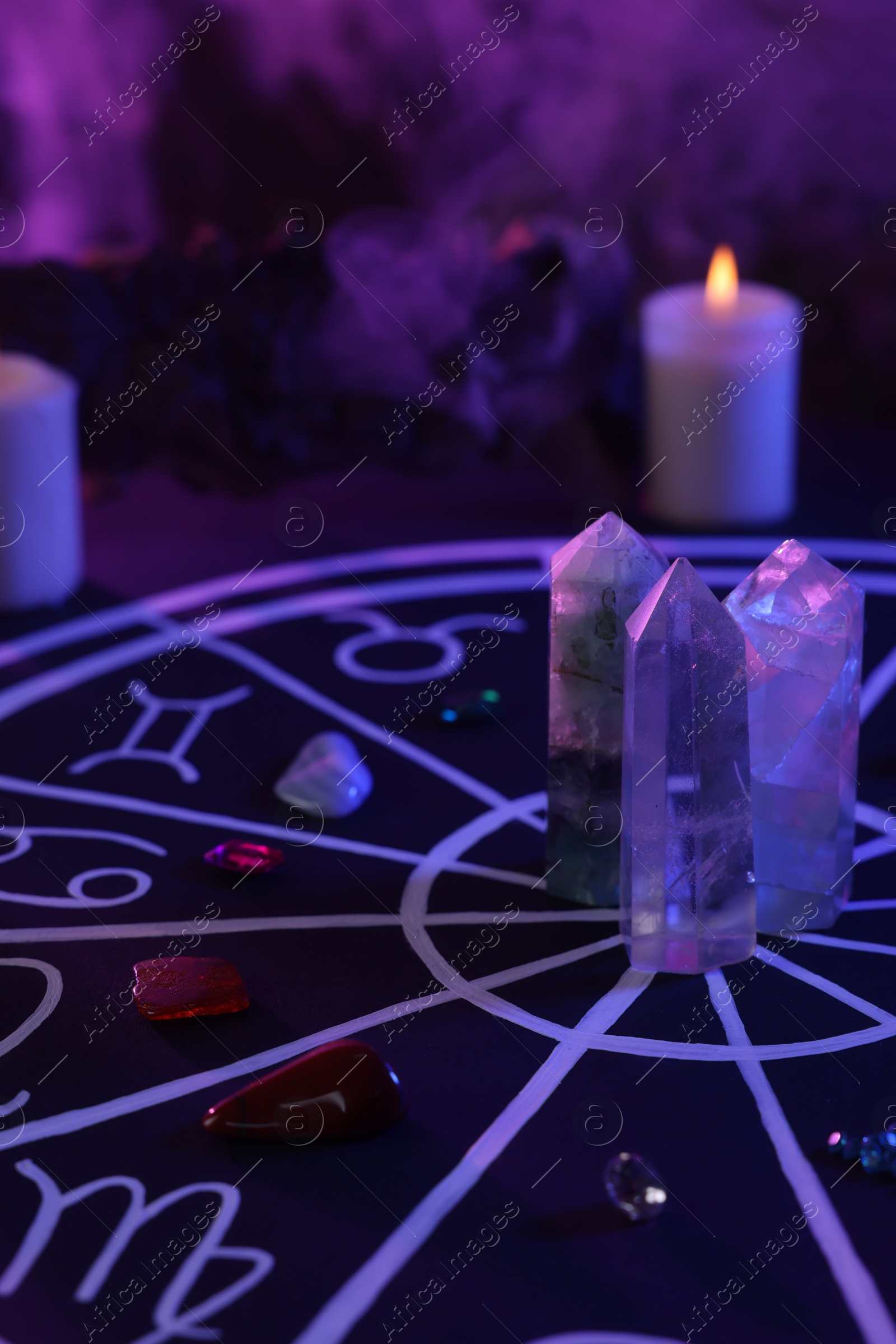 Photo of Natural stones for zodiac signs, drawn astrology chart and burning candles on black table. Color tone effect