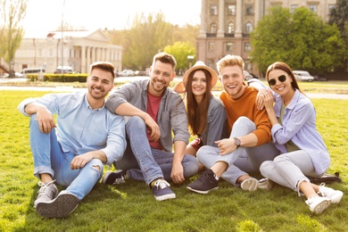 Happy people sitting on green grass in park