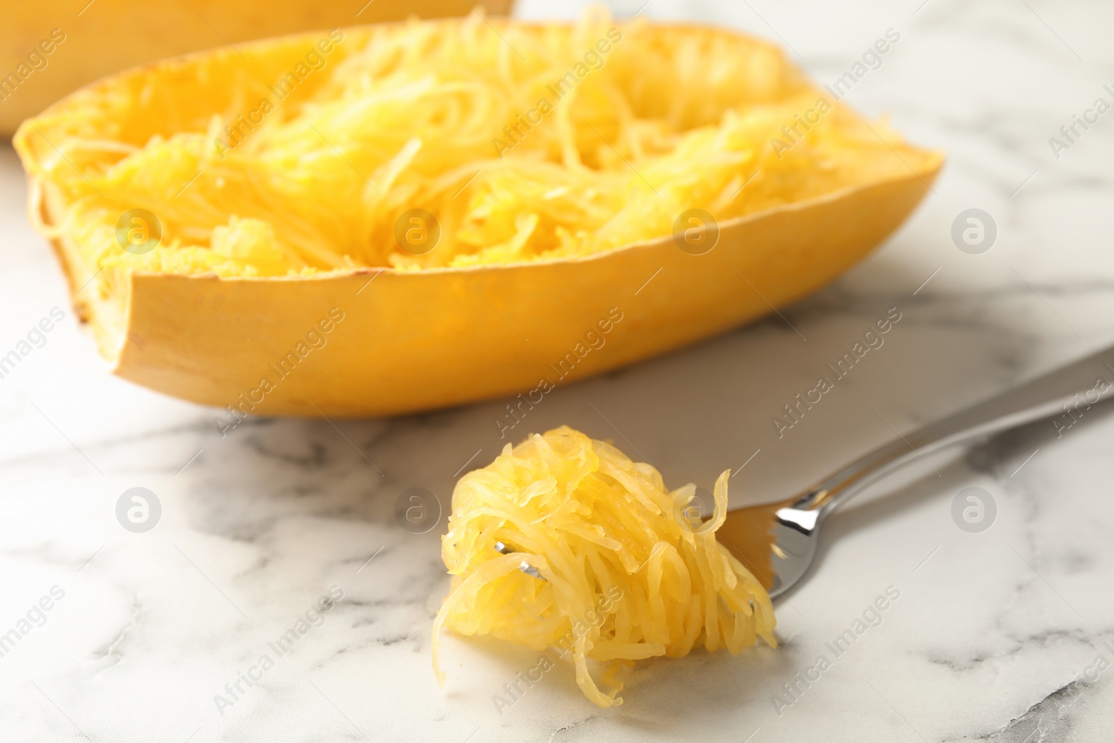 Photo of Fork with flesh near cooked spaghetti squash on table