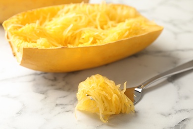 Fork with flesh near cooked spaghetti squash on table