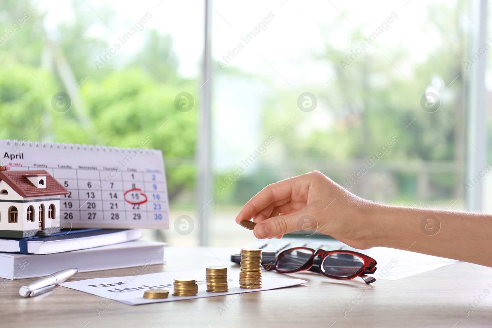 Photo of Woman stacking coins on table. Tax calculation