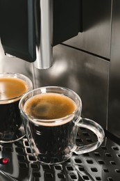 Photo of Modern espresso machine with glass cups of coffee, closeup
