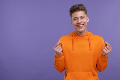 Photo of Happy man showing money gesture on purple background. Space for text