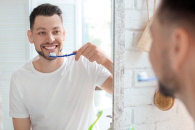 Young man brushing his teeth in bathroom