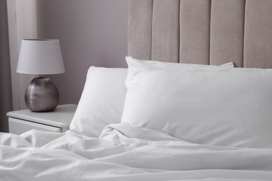 Photo of White soft pillows on bed and lamp in room