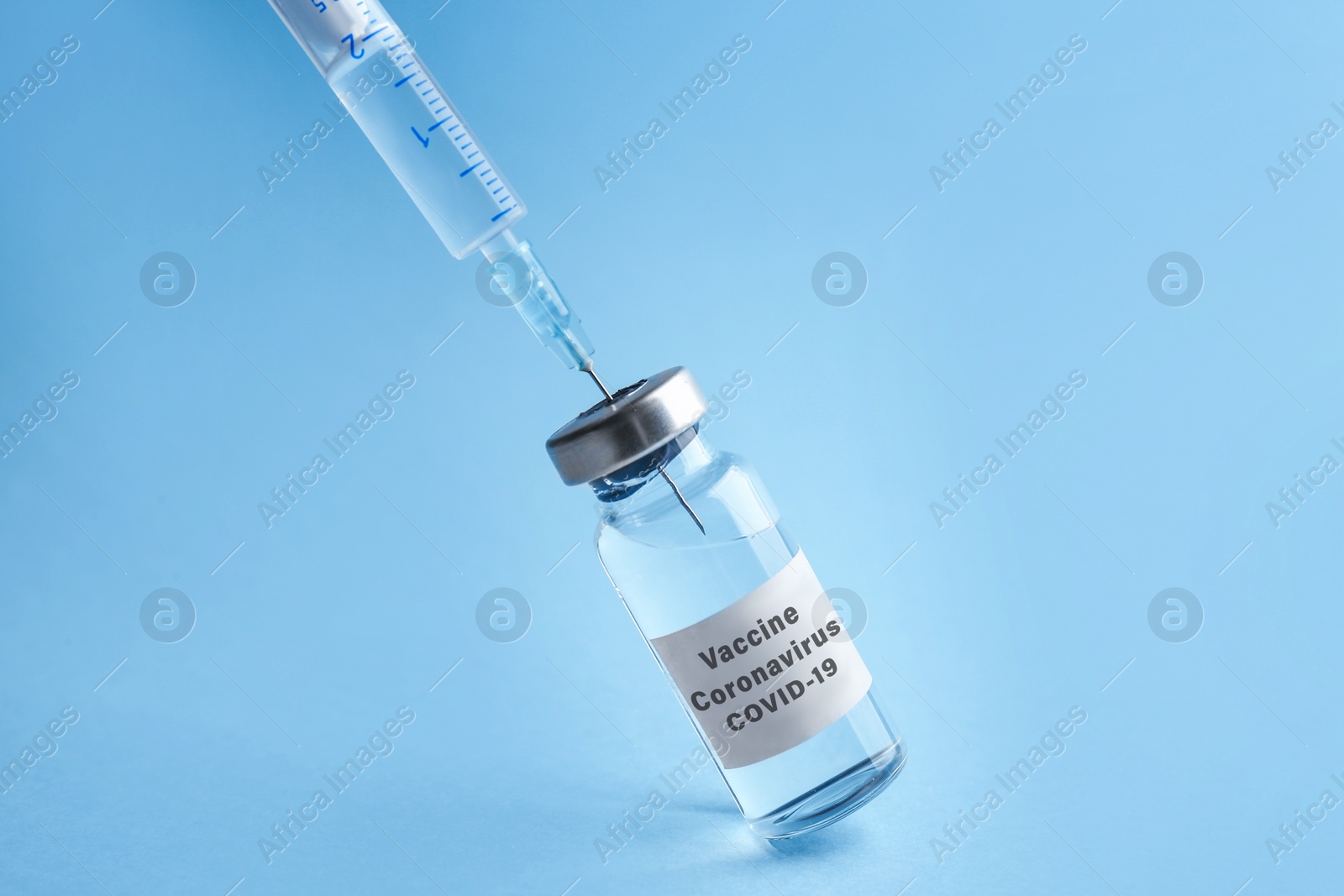 Image of Filling syringe with coronavirus vaccine on light blue background