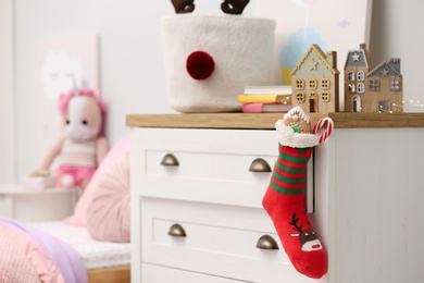 Photo of Stocking with presents hanging on drawer in children's room. Saint Nicholas Day tradition