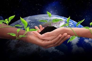 Make Earth green. Man and woman holding soil with seedling, closeup view of their hands tied with creeping plant. Globe in space on background