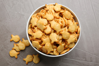Photo of Delicious goldfish crackers in bowl on grey table, flat lay