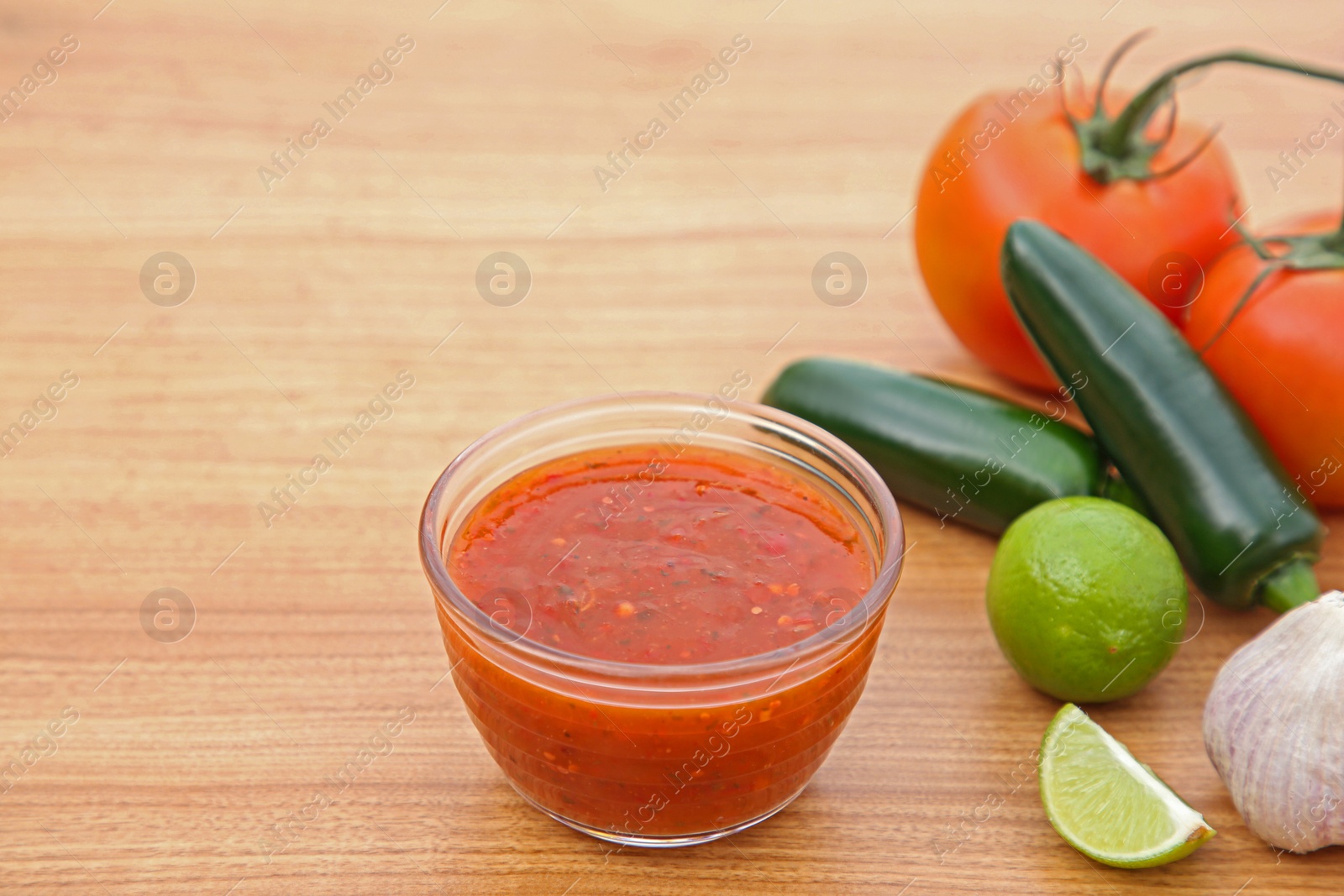 Photo of Tasty salsa sauce and different ingredients on wooden table. Space for text