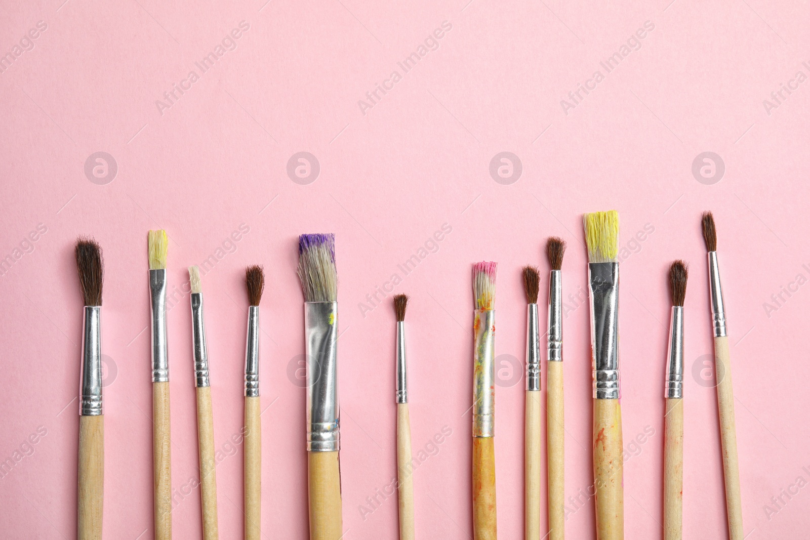 Photo of Different paint brushes on color background, top view with space for text