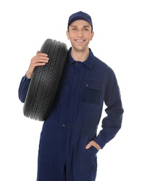 Young mechanic in uniform holding car tire on white background