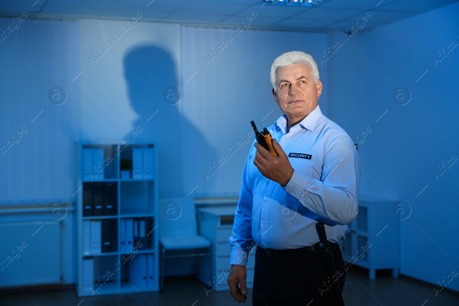 Photo of Professional security guard with portable radio set in dark room