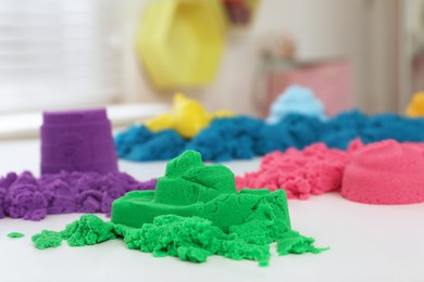Photo of Colorful kinetic sand on white table indoors