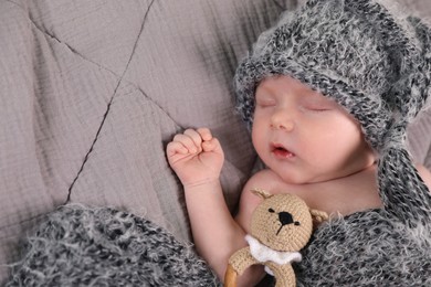 Cute newborn baby sleeping with teething toy in bed, top view